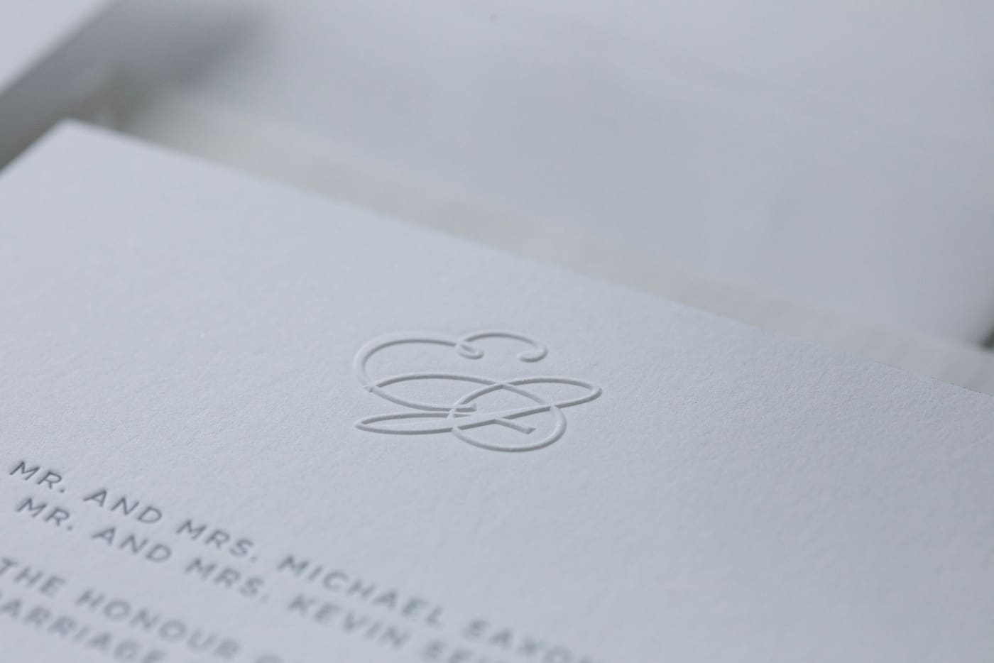 A blind embossing of a monogram with the letters "E" and "J" on wedding invitations