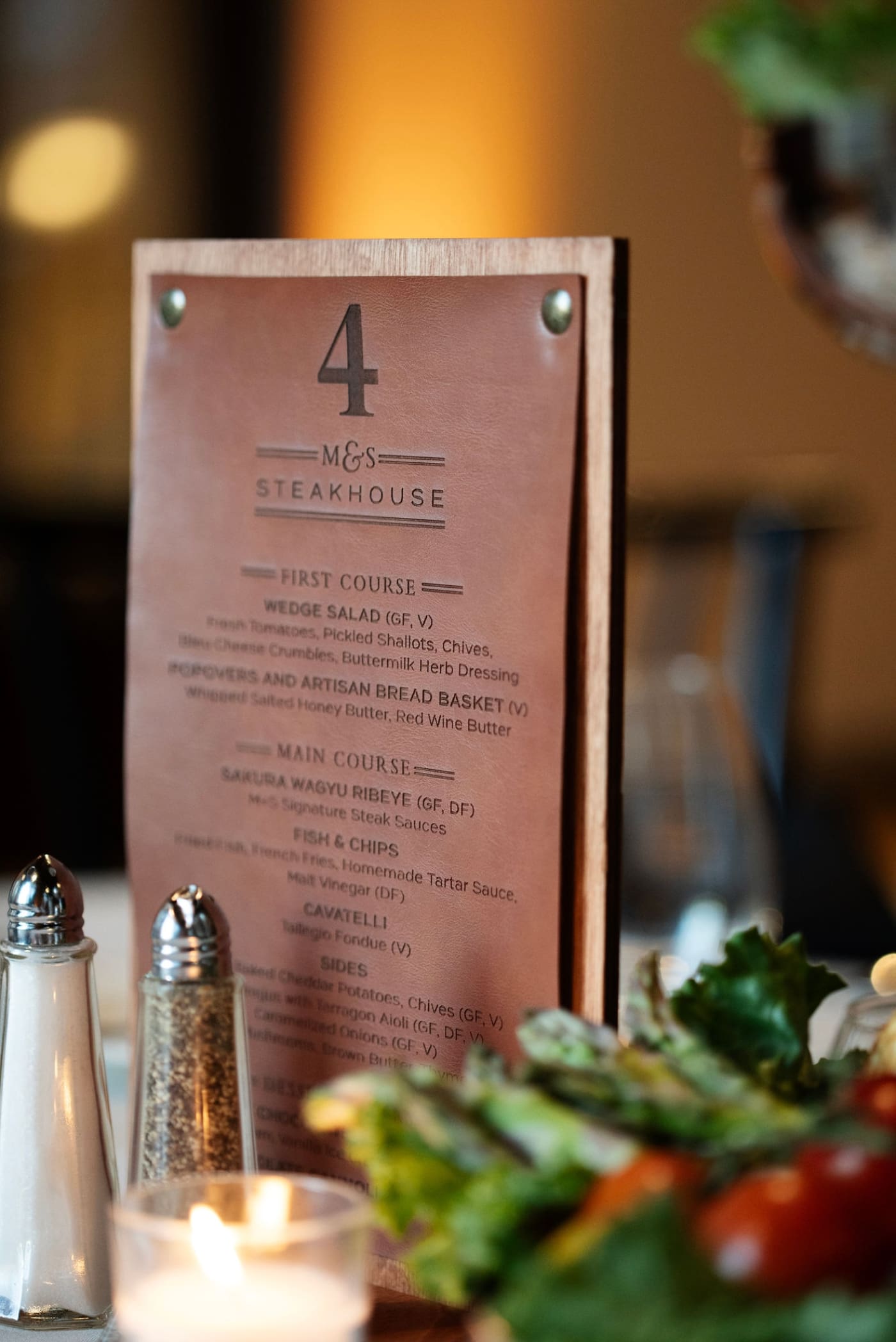 A menu for a wedding rehearsal dinner embossed onto leather and pinned onto wood