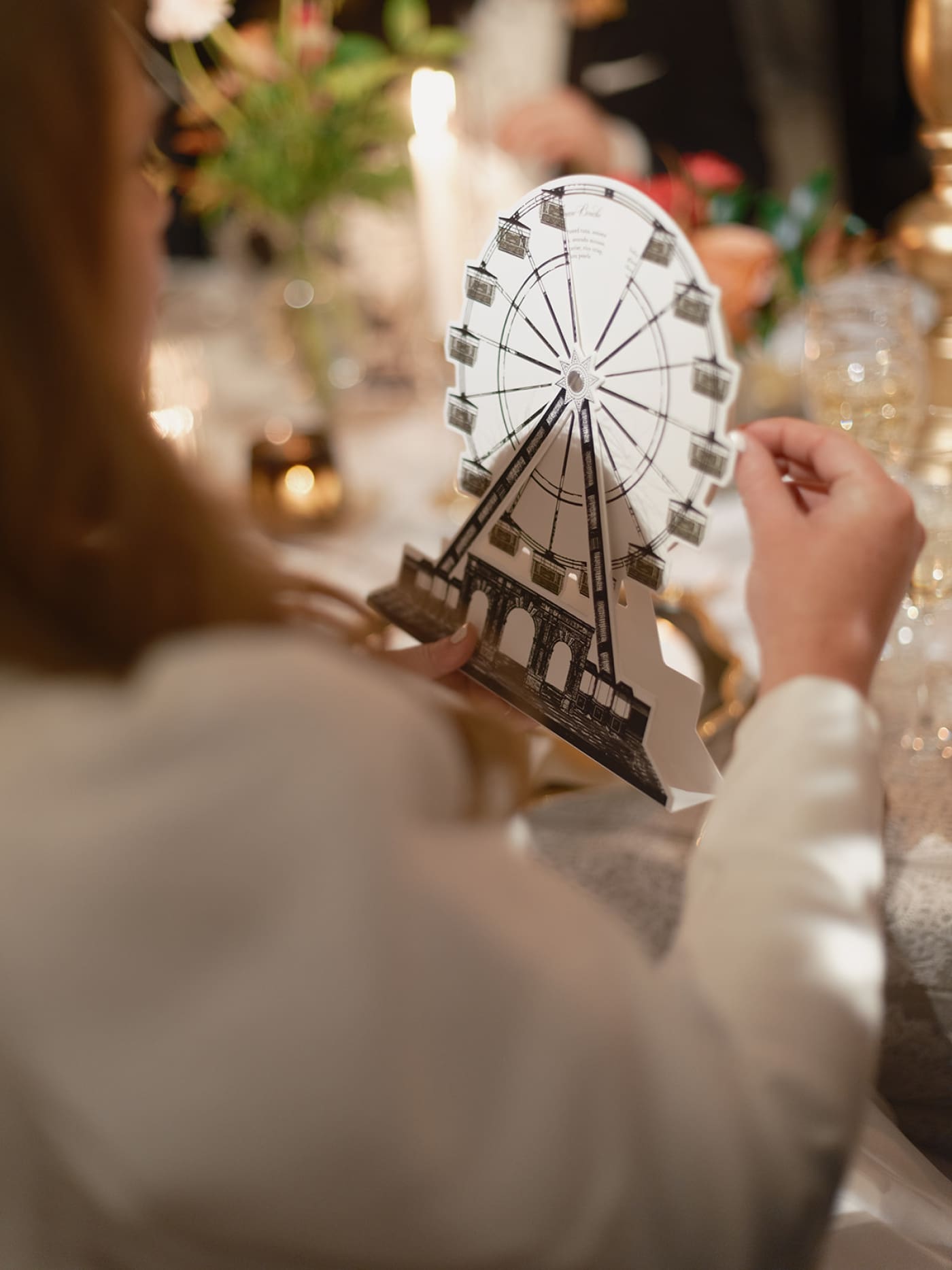 A woman holds a paper ferris wheel which turns and reveals menu options at a wedding reception